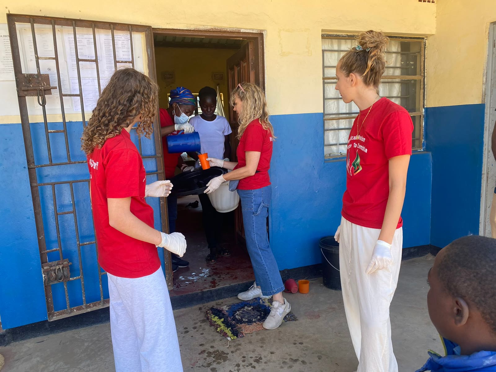 Volunteers in red shirts at a clinic doorway