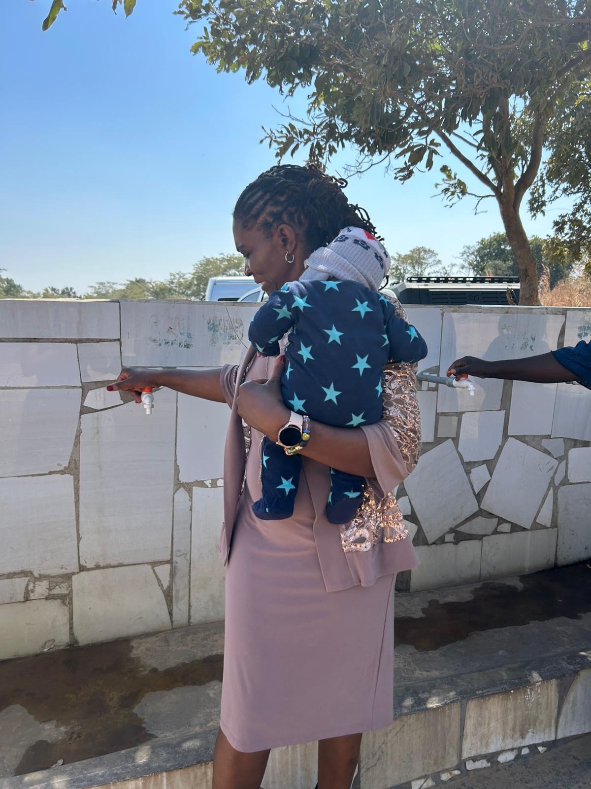 Mother with child accessing clean water at community well